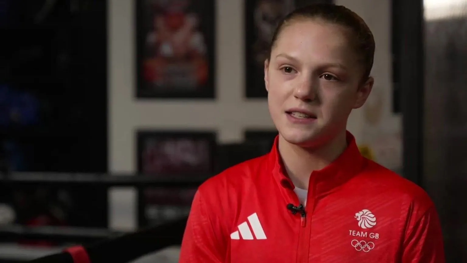 BBC Lily Bassett in a red Team GB sports top in a boxing gym.