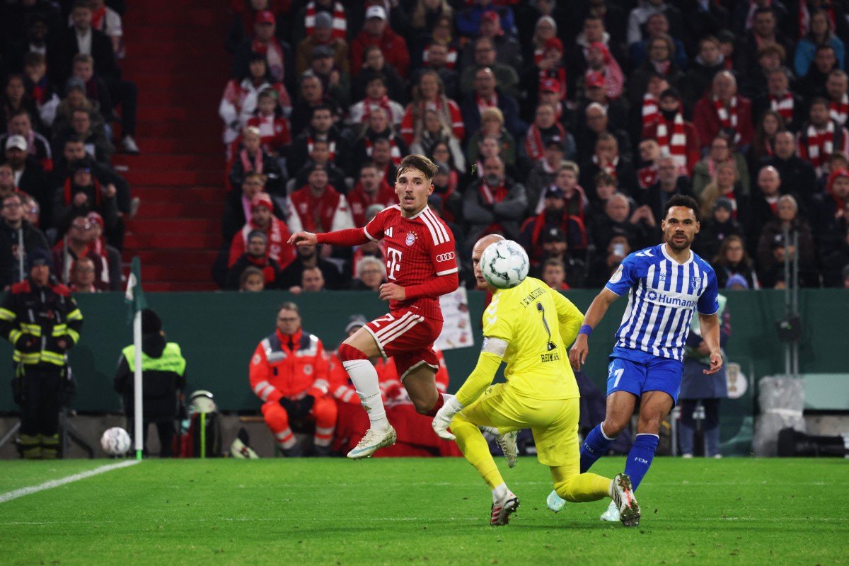 Bayern Munich's German midfielder #42 Lennart Karl (C) kicks the ball past Magdeburg's German goalkeeper #01 Dominik Reimann (L) and Magdeburg's Ugandan defender #07 Herbert Bockhorn (R) for the 4-1 goal during the German Cup (DFB-Pokal) football match between FC Bayern Munich and 1. FC Magdeburg in Munich, southern Germany on October 28, 2026.