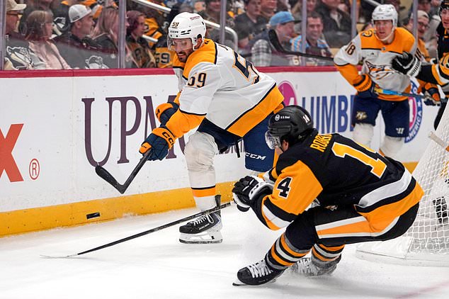 Nashville Predators' Roman Josi (59) clears the puck before Pittsburgh Penguins' Nick Robertson (14) can get to it during the second period of an NHL hockey game in Pittsburgh, Saturday, Oct. 24, 2026. (AP Photo/Gene J. Puskar)