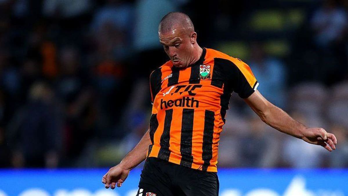 Jack Maskell looks down as he controls the ball, wearing Barnet orange and black home kit