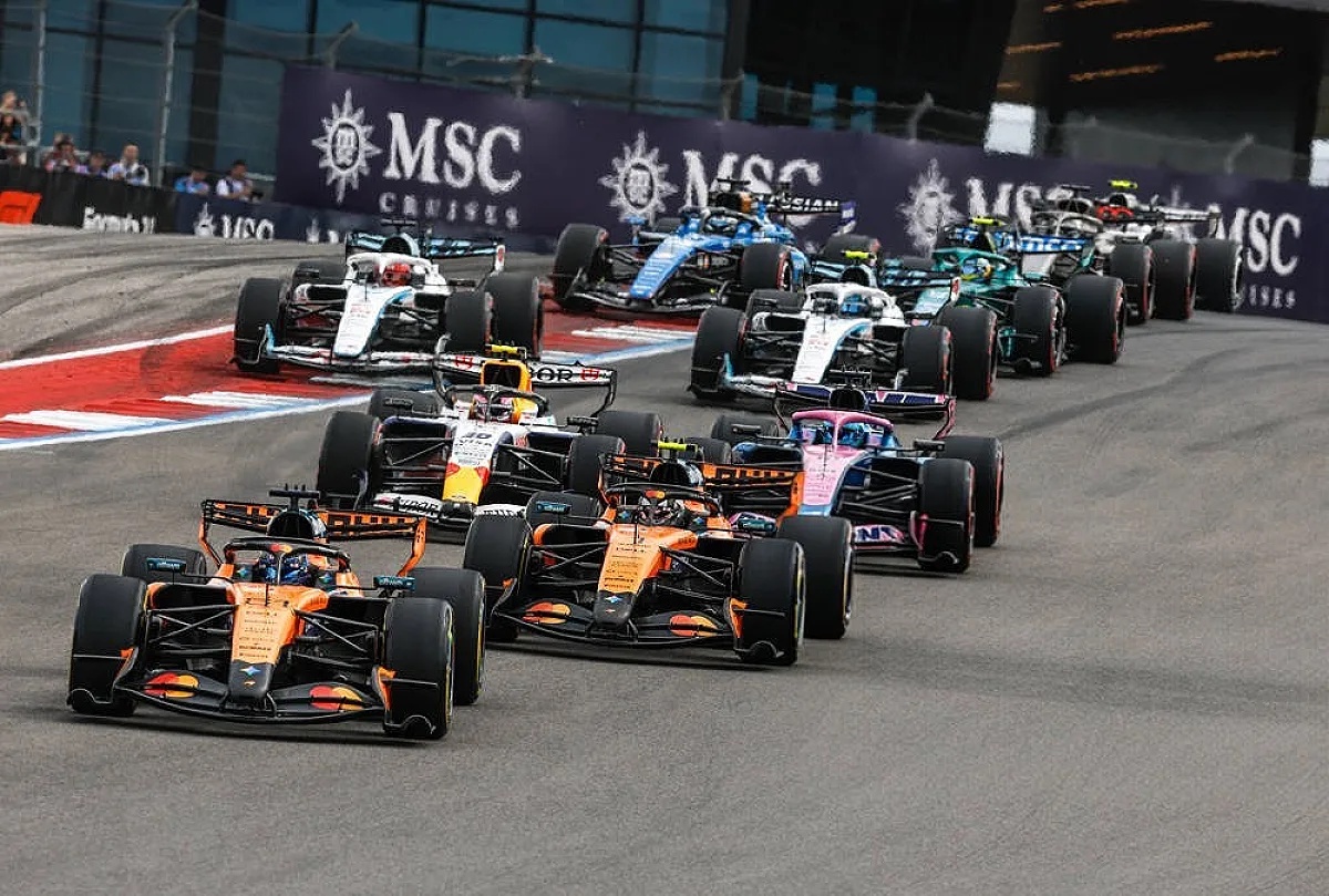 Formula 1 cars racing in a pack at the US GP, with orange McLaren cars leading past MSC Cruises branded barriers