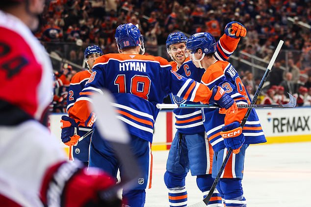 Edmonton Oilers' Zach Hyman (18), Connor McDavid (97) and Ryan Nugent-Hopkins, right, celebrate after Nugent-Hopkins' goal against the Carolina Hurricanes during the second period of an NHL hockey game in Edmonton, Alberta, Thursday, Oct. 22, 2026. (Codie McLachlan/The Canadian Press via AP)