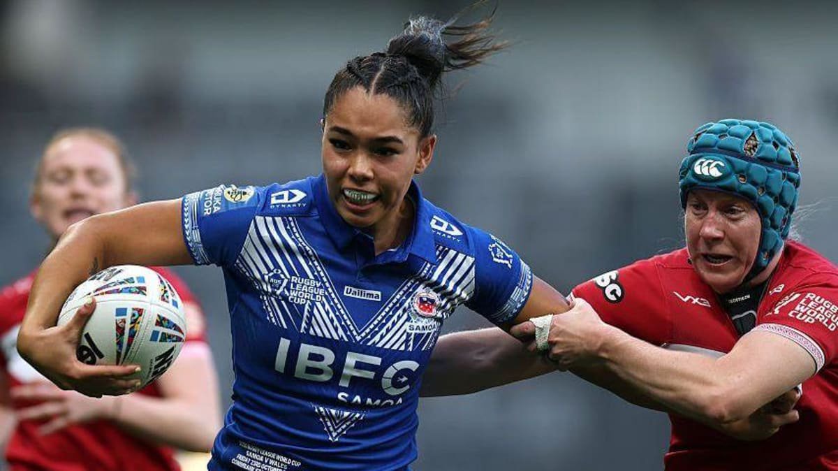 Wales player in red tries to tackle blue-shirted ball carrier Tyra Ekepati as she scores a try on her Samoa debut