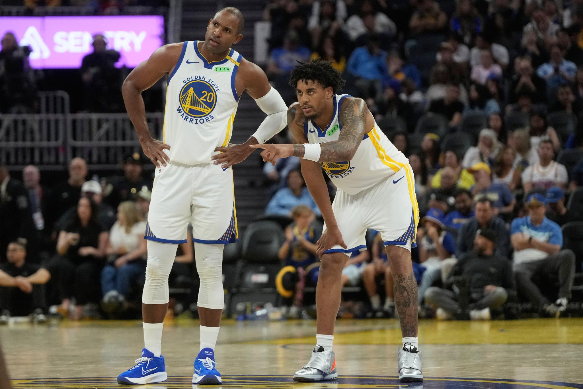 Golden State Warriors center Al Horford and forward Yaxel Lendeborg talk on the court during a game.