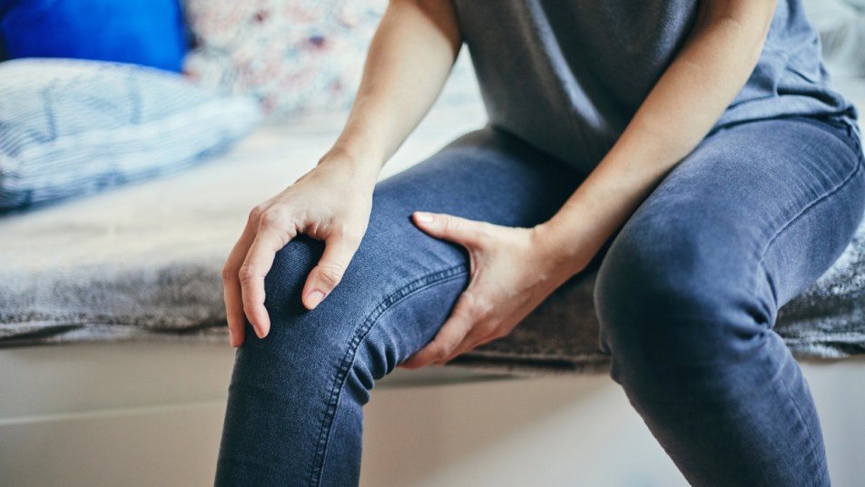 A close-up of a woman touching her knee, which has pain on the inside