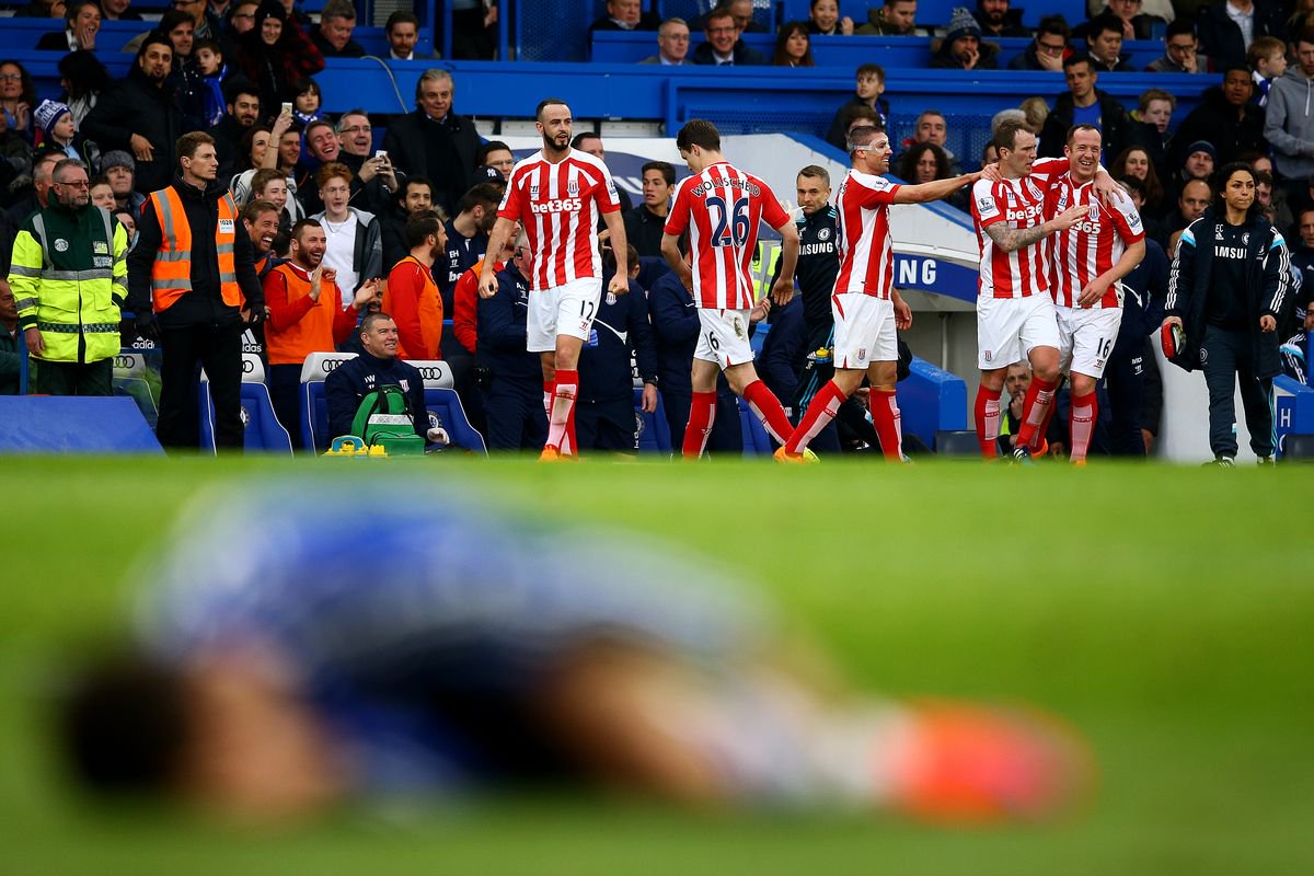 Charlie Adam of Stoke City celebrates with team-mates after scoring his team's first goal as Eden Hazard of Chelsea lies on the floor during the Barclays Premier League match between Chelsea and Stoke City at Stamford Bridge