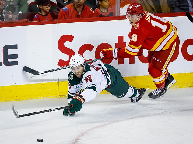 Minnesota Wild's Ryan Hartman, left, is checked by Calgary Flames' Ben Jones, right, during the third period of an NHL hockey game in Calgary, Alberta, Thursday, Oct. 22, 2026. (Jeff McIntosh/The Canadian Press via AP)