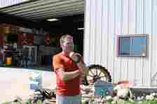 Mental health advocate Jason Haglund stands outside a machine shed on his family’s farm near Boone on May 17. He has seen how farmers’ traditional self-sufficiency can make them hesitate to seek help for mental stress. (Tony Leys/KFF Health News)