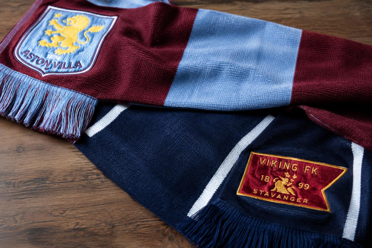 The scarf of Aston Villa FC with its logo placed on the top left corner is put above the scarf of Viking Stavanger FK with it