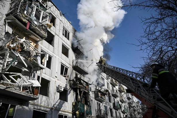 Firefighters work on a fire on a building after bombings on the eastern Ukraine town of Chuguiv
