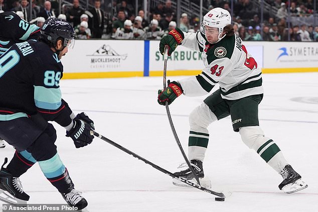 Seattle Kraken center Frederick Gaudreau (89) blocks a shot from Minnesota Wild defenseman Quinn Hughes (43) during the first period of an NHL hockey game Saturday, Oct. 24, 2026, in Seattle. (AP Photo/Lindsey Wasson)