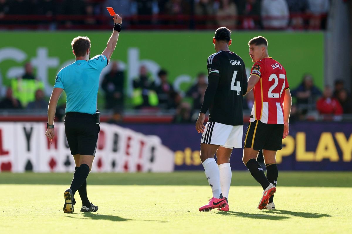 Referee John Brooks shows a red card to Yehor Yarmolyuk of Brentford  as Virgil van Dijk of Liverpool and Vitaly Janelt of Brentford look on. 