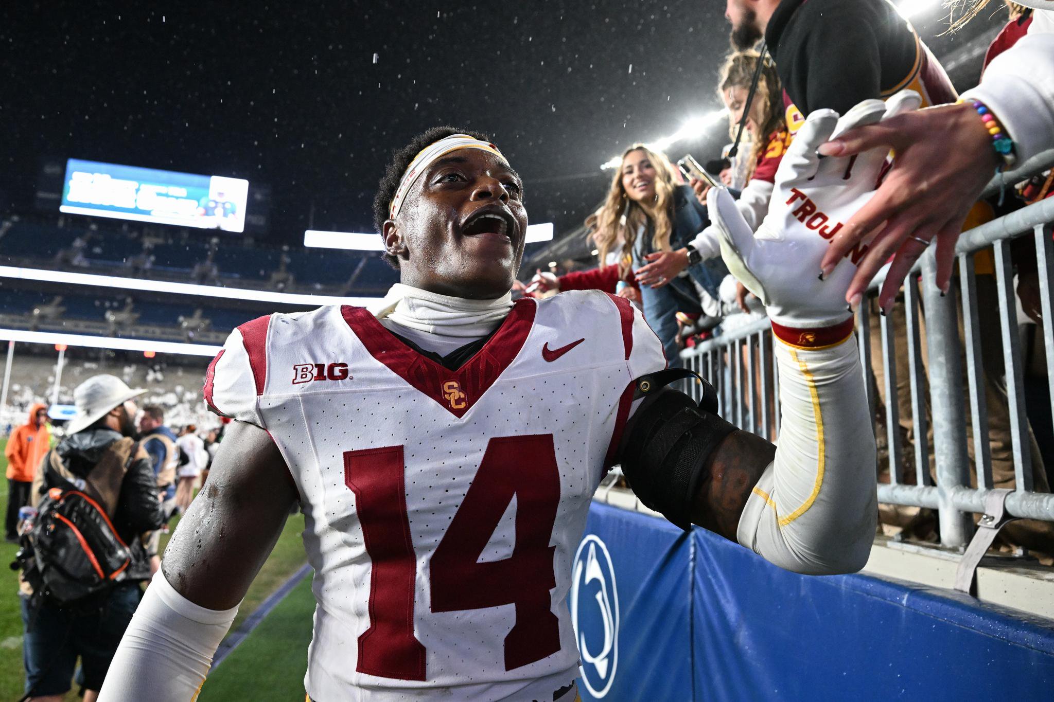A USC football player celebrates with fans in the stands after a game against Penn State.