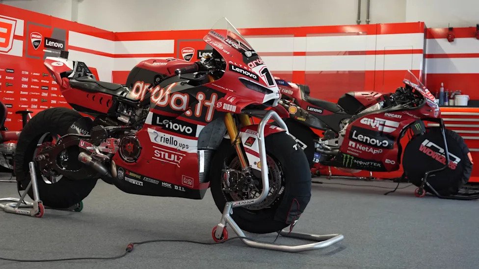 Two Ducati motorcycles, one WorldSBK and one MotoGP, in a garage