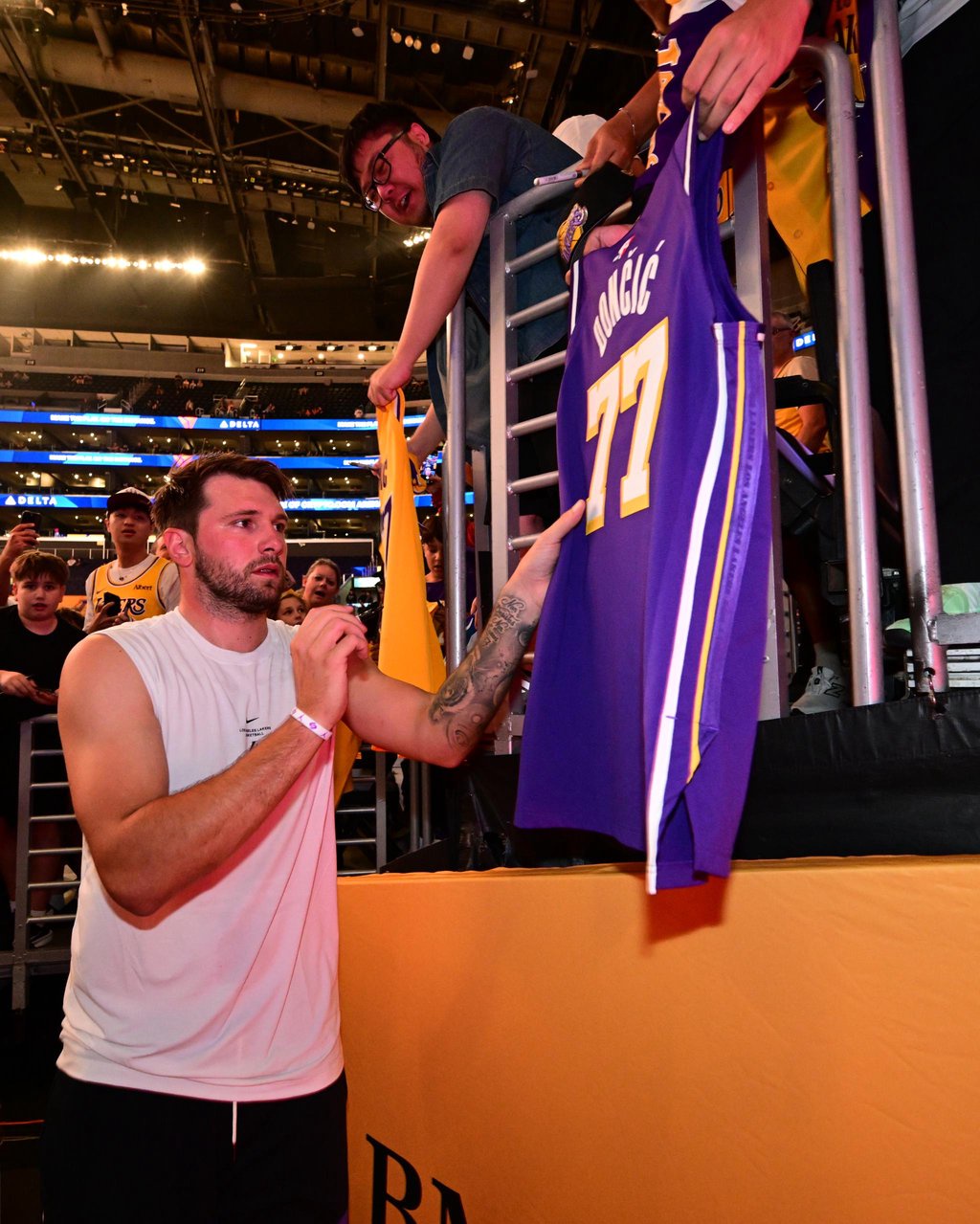 Luka Doncic signs a jersey for a fan in the stands.