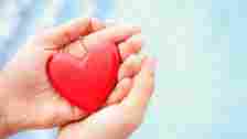 hands holding a red heart shape against blue background symbolizing health. earnings outperformers