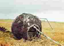 Battered Vostok-1 space capsule in a field in Russia.