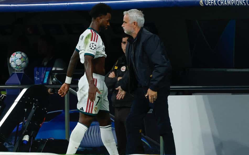 O atacante brasileiro do Real Madrid, número 7, Vinicius Junior (E), passa pelo técnico português do Real Madrid, José Mourinho, ao ser substituído durante a partida da 3ª rodada da Liga dos Campeões da UEFA entre Real Madrid CF e RB Leipzig, no estádio Santiago Bernabéu, em Madri, em 21 de outubro de 2026. (Foto: Oscar Del Pozo / AFP)