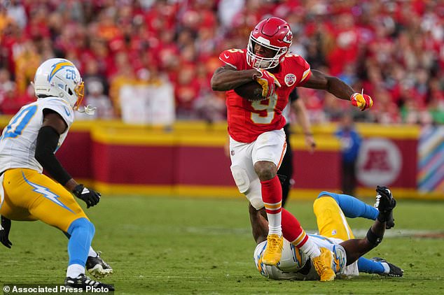 Kansas City Chiefs running back Kenneth Walker III (9) escapes a tackle attempt by Los Angeles Chargers linebacker Del'shawn Phillips, bottom, as Cam Hart (20) moves in to make this stop during the second half of an NFL football game in Kansas City, Mo., Sunday, Oct. 18, 2026. (AP Photo/Ed Zurga)
