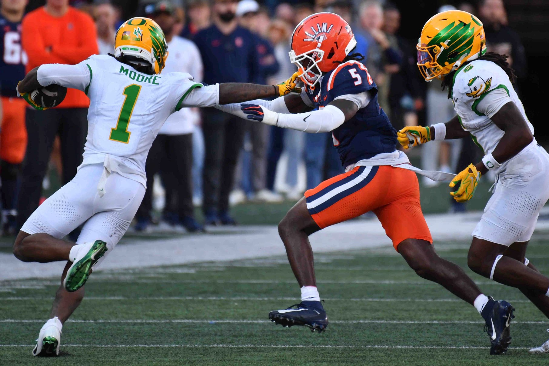Oct 24, 2026; Champaign, Illinois, USA;  Oregon Ducks wide receiver Dakorien Moore (1) stiff arms Illinois Fighting Illini defensive back Jakwon Morris (5) on a run during the second half at Gies Memorial Stadium.  Mandatory Credit: Ron Johnson-Imagn Images