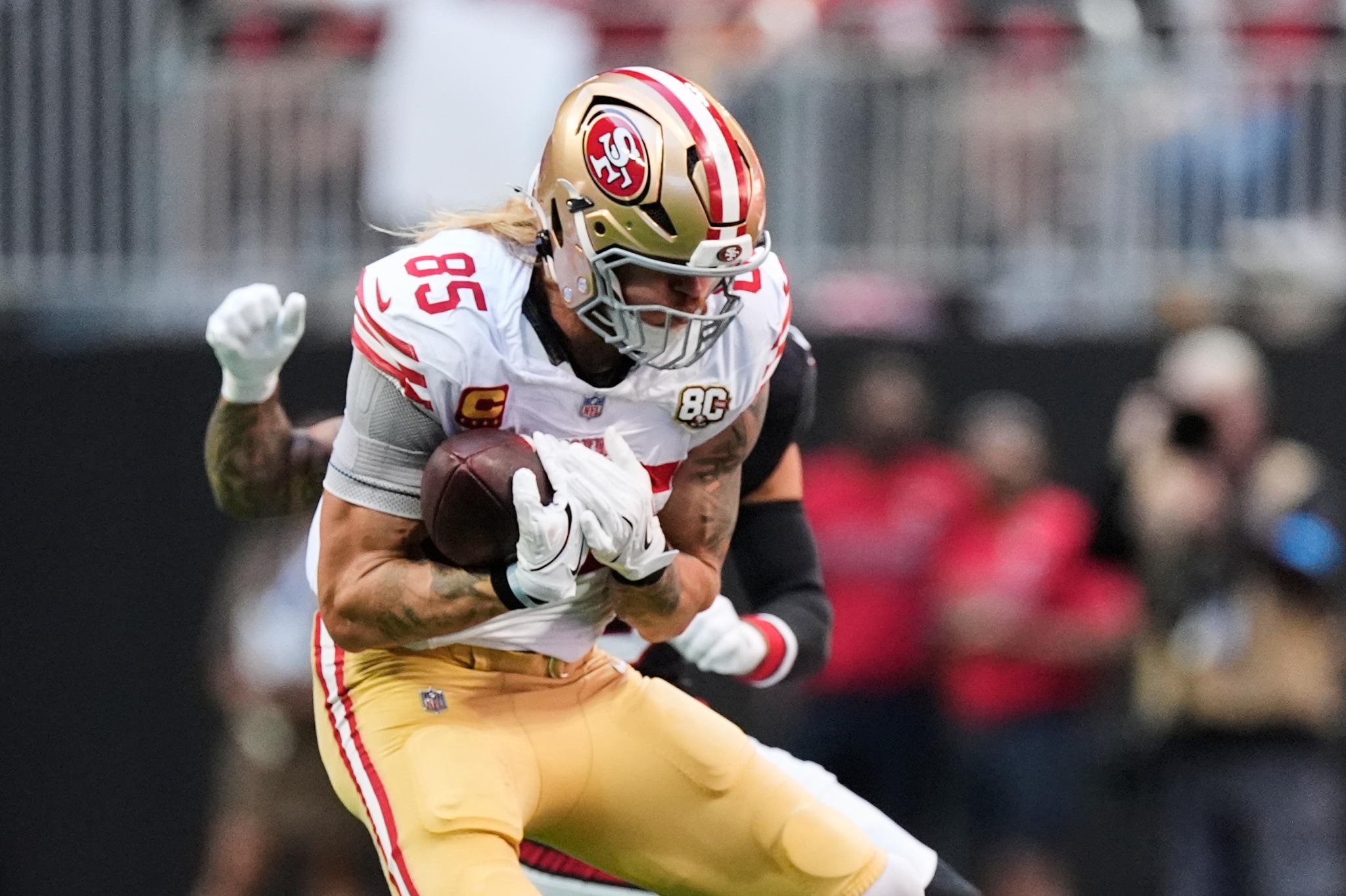 George Kittle running with the football during a game.