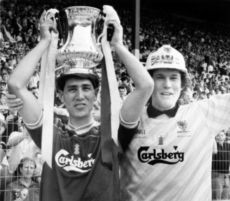 Wimbledon FC player Lawrie Sanchez holds the FA Cup as his captain and goalkeeper David Beasant acknowledges the cheers of their fans on May 14, 1988