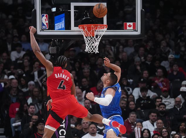 Orlando Magic's Nikola Vucevic, right, and Toronto Raptors' Scottie Barnes (4) battle for a loose ball during the first half of an NBA basketball game in Toronto, Wednesday, Oct. 28, 2026. (Nathan Denette/The Canadian Press via AP)