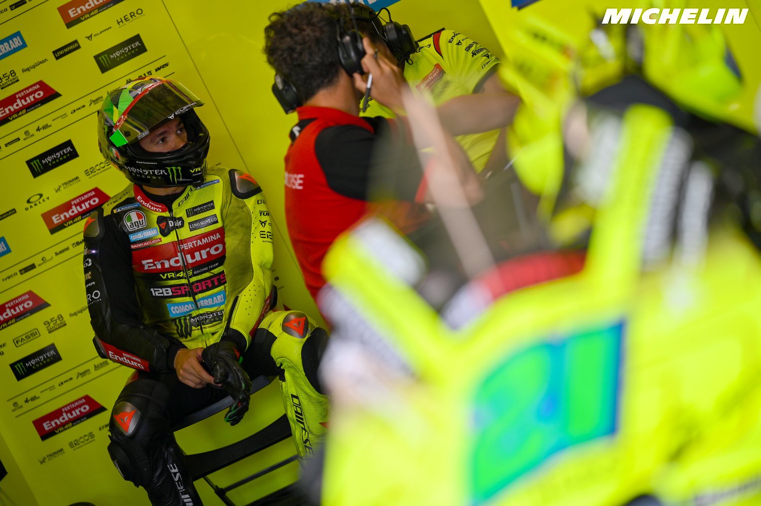 Franco Morbidelli in yellow and green VR46 leathers seated in the MotoGP pit garage, wearing a helmet and gloves