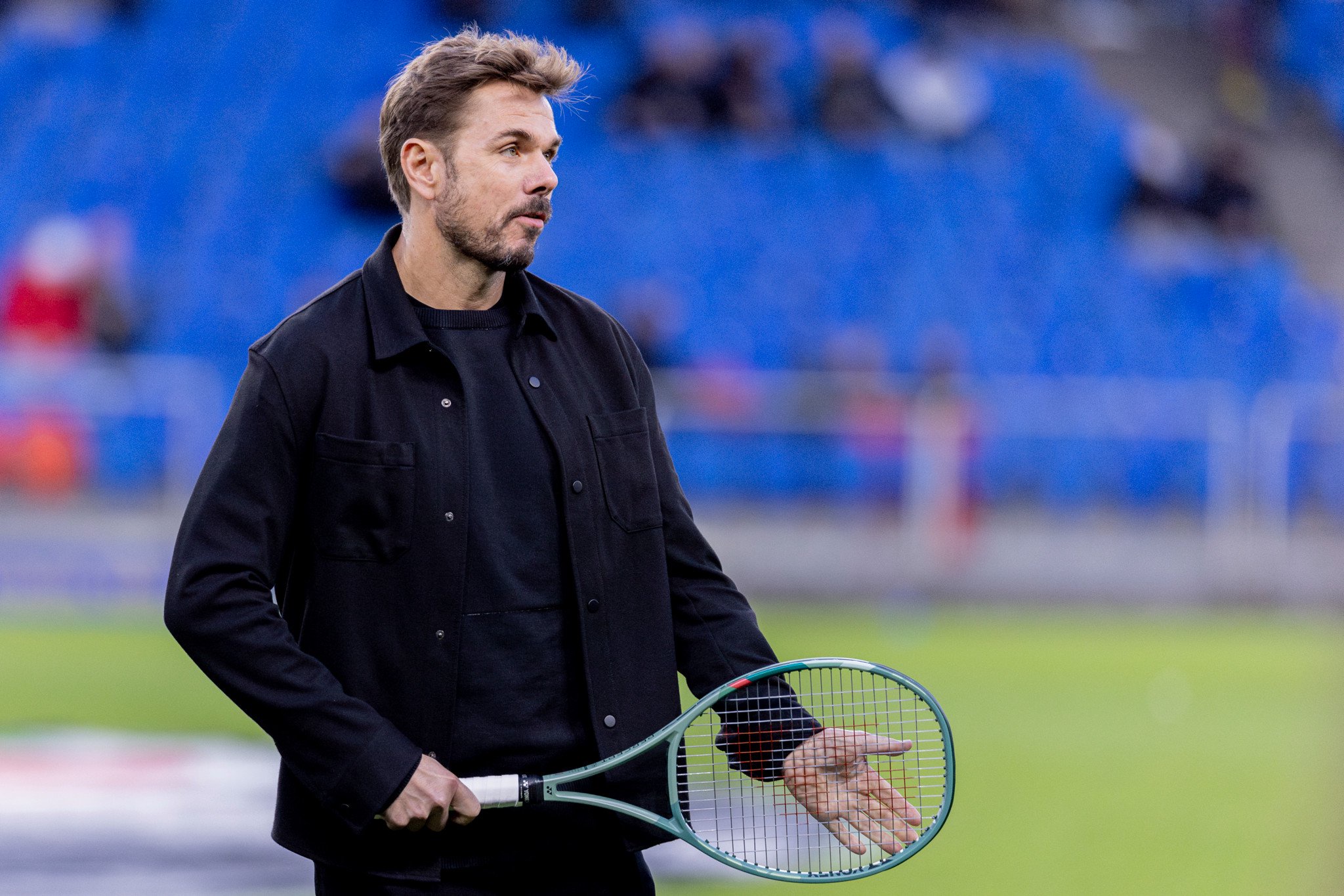 Stan Wawrinka tenant une raquette de tennis sur la pelouse du stade lors du match FC Basel – Grasshopper Club Zürich en Super League.