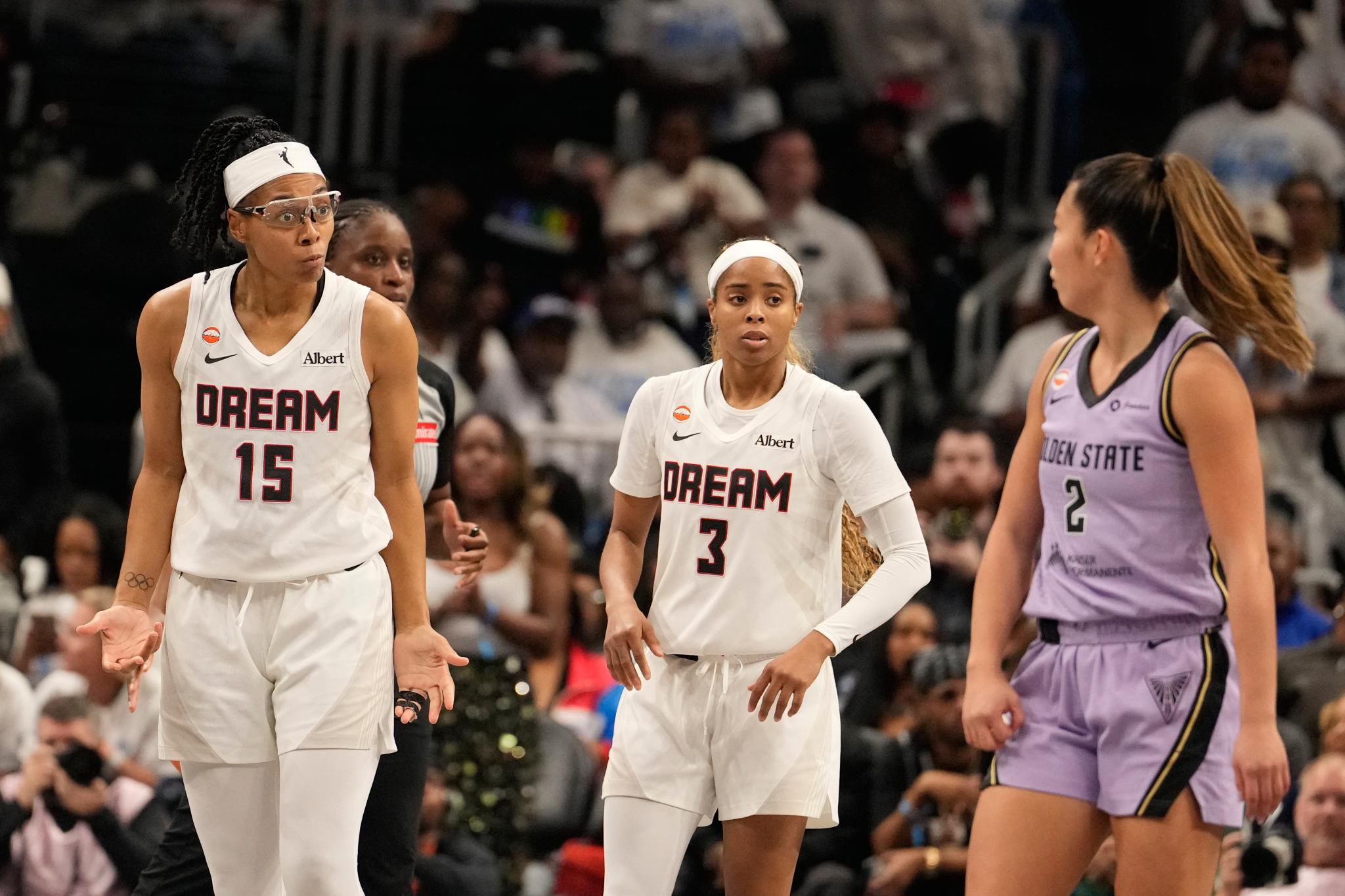 Two Atlanta Dream players, #15 and #3, stand on the court during a WNBA game, facing an opposing player.