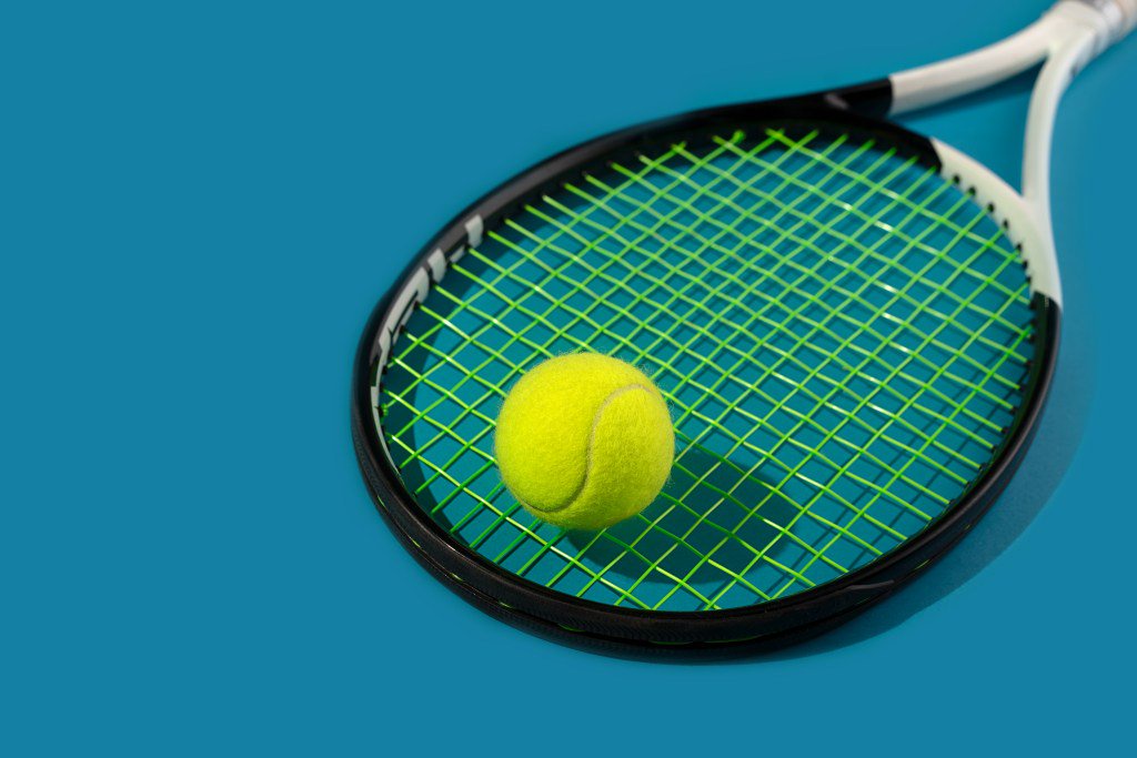 Sport Concept with Tennis Ball and Tennis Racket on Blue Hard Tennis Court Background with shadow.