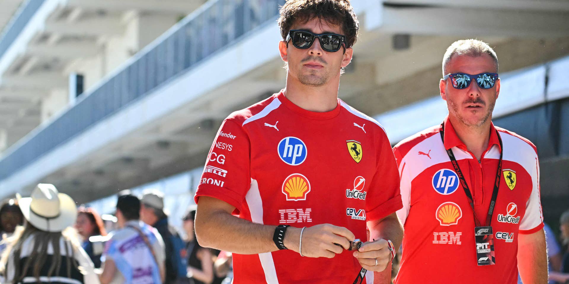 Ferrari-Formel-1-Pilot Charles Leclerc läuft in roter Teamkleidung und mit Sonnenbrille durch die Boxengasse in Austin.