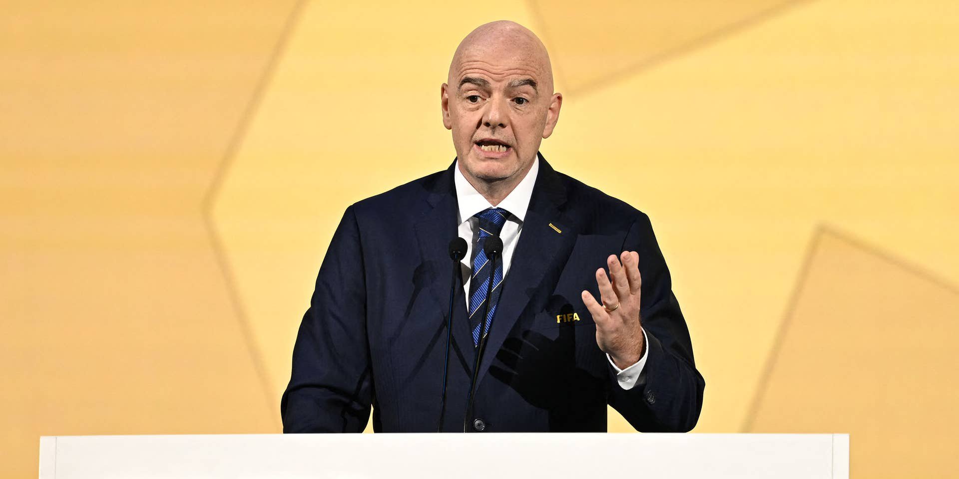 Ein Mann im Anzug spricht bei einem FIFA-Kongress an einem Podium mit FIFA-Logo.