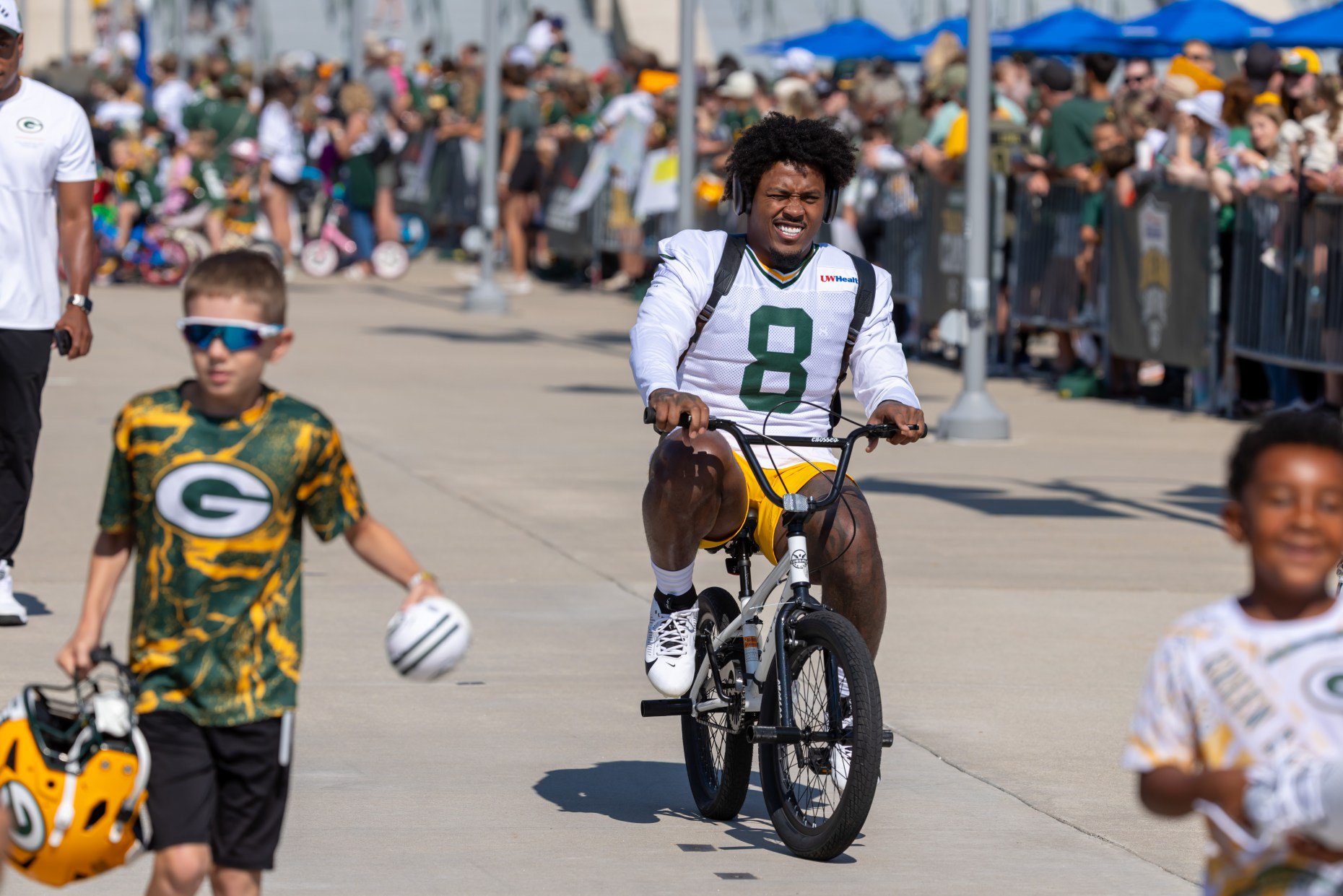 Green Bay Packers running back Josh Jacobs (8) rides a fan's bicycle to the NFL football team's training camp, Sunday, Aug. 2, 2026, in Green Bay, Wis. (AP Photo/Mike Roemer)