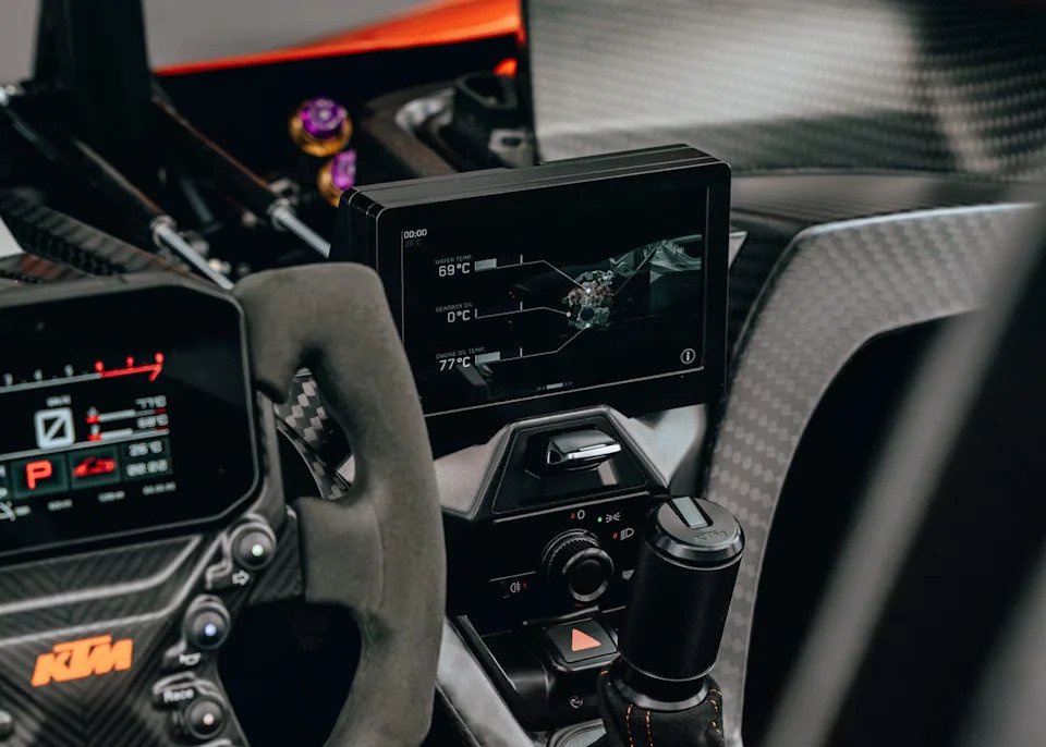 Dashboard view of a sports car with digital display showing engine and fluid temperatures.