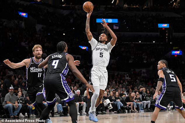 San Antonio Spurs guard Stephon Castle (5), center, shoots against Sacramento Kings forward Precious Achiuwa (9) during the first half of an NBA basketball game, Tuesday, Oct. 27, 2026, in San Antonio. (AP Photo/Darren Abate)