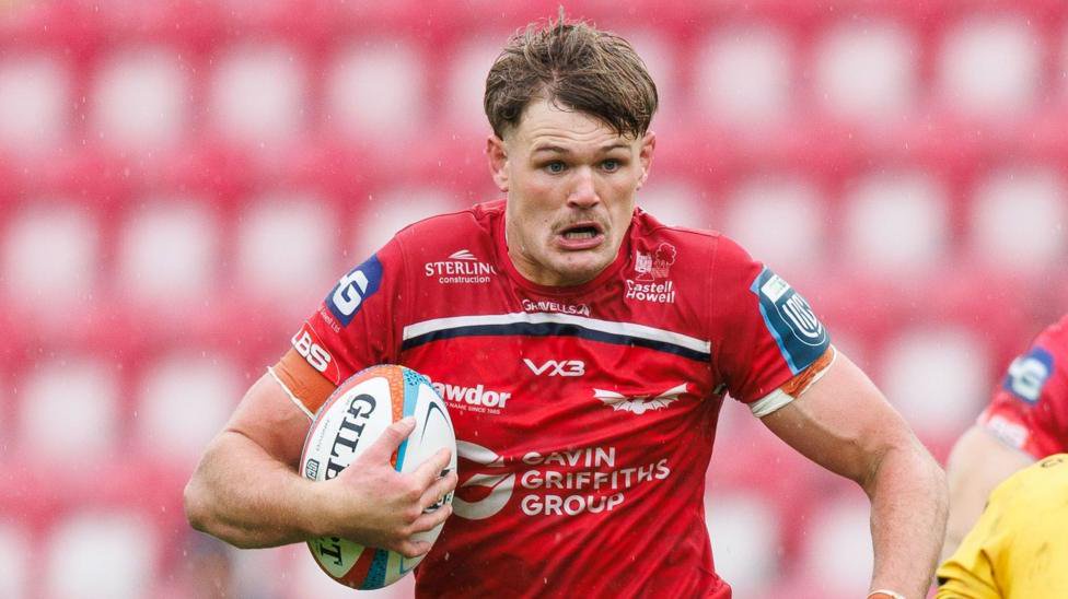 Taine Plumtree runs with the ball under his right arm for Scarlets