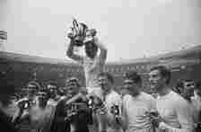 Leeds United FC captain Billy Bremner (1942 - 1997) and fellow soccer players hold trophies after winning the  Football League Cup Final against Ar...