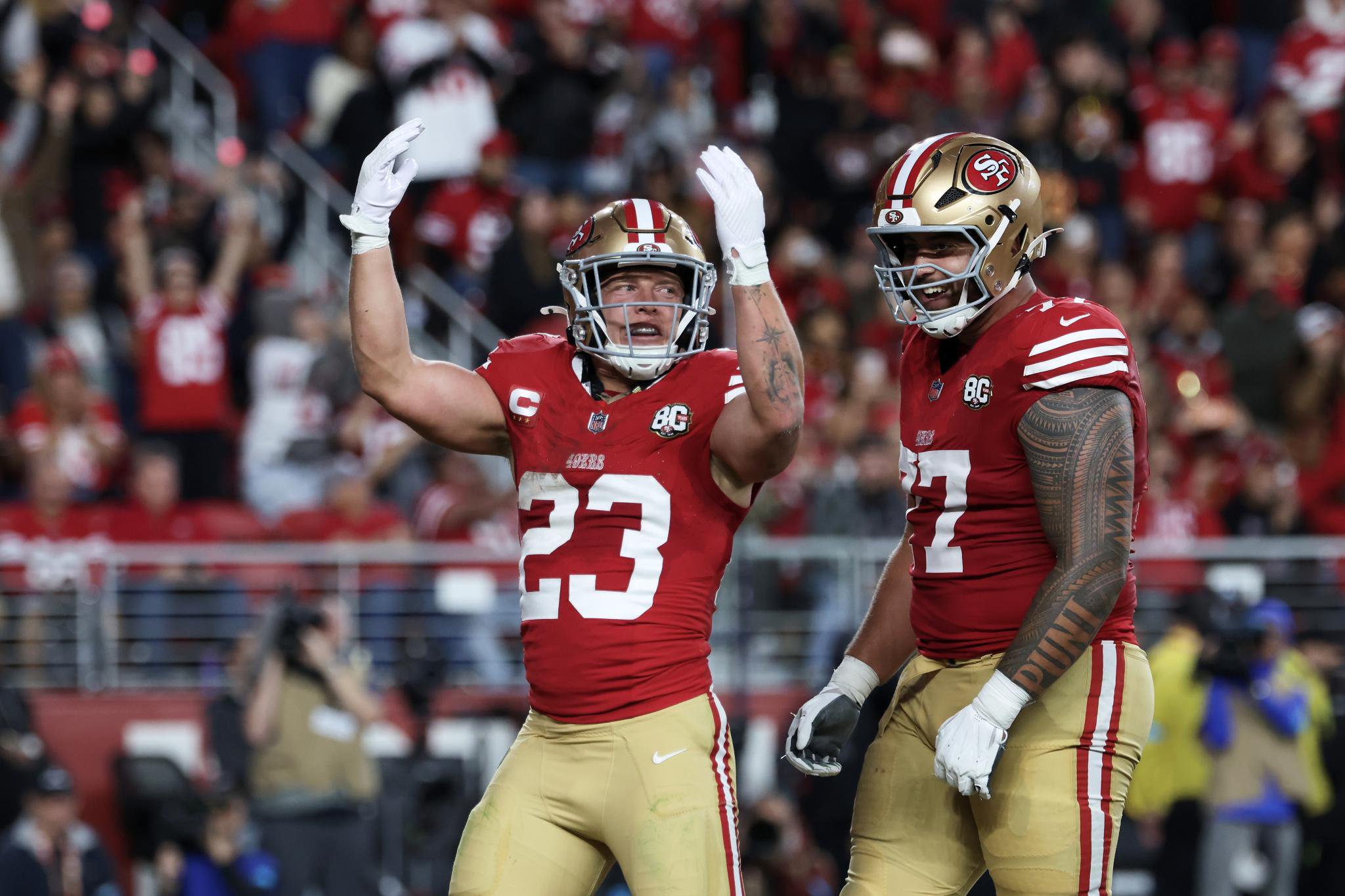 Christian McCaffrey and Dominick Puni celebrating on the field.