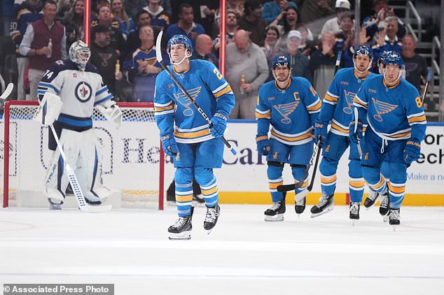 St. Louis Blues' Jimmy Snuggerud, second from left, skates off the ice after scoring past Winnipeg Jets goaltender Stuart Skinner (74) during the first period of an NHL hockey game Tuesday, Oct. 20, 2026, in St. Louis. (AP Photo/Jeff Roberson)
