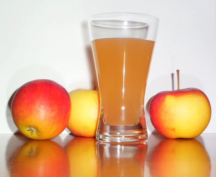 apple juice in a glass cup with 3 apples