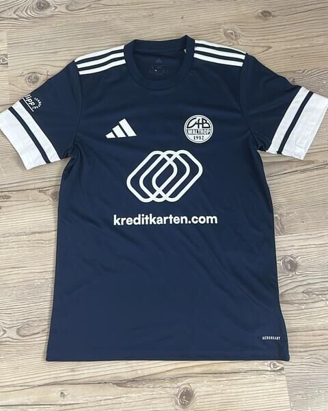 Beim Heimtrikot des VfB Waltrop bildet Dunkelblau die Grundlage, weiße Schulterstreifen und Ärmelabschlüsse setzen klare Akzente.