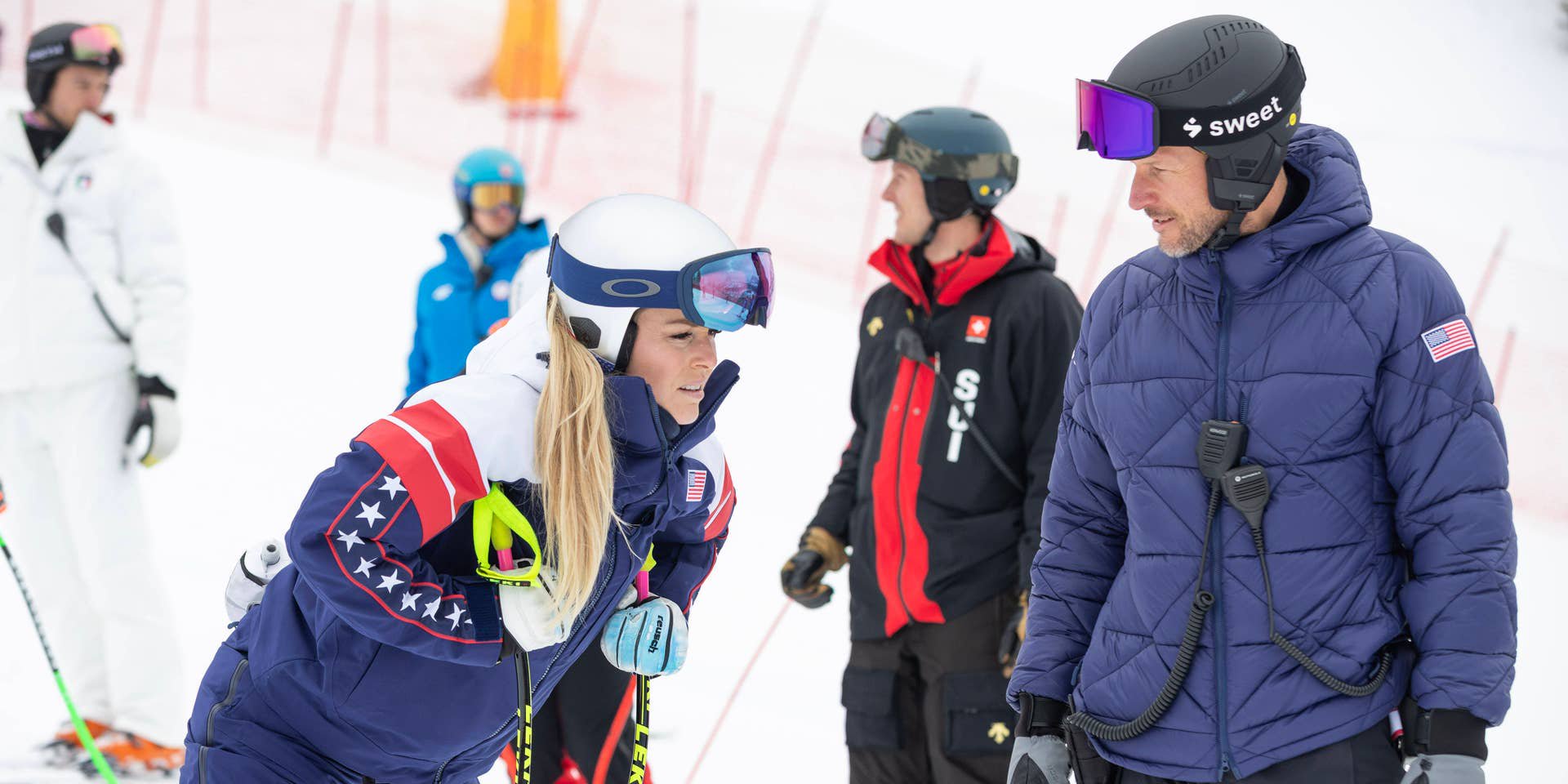 Skifahrerin im Team-USA-Anzug spricht mit ihrem Trainer auf einer Skipiste während der Inspektion.