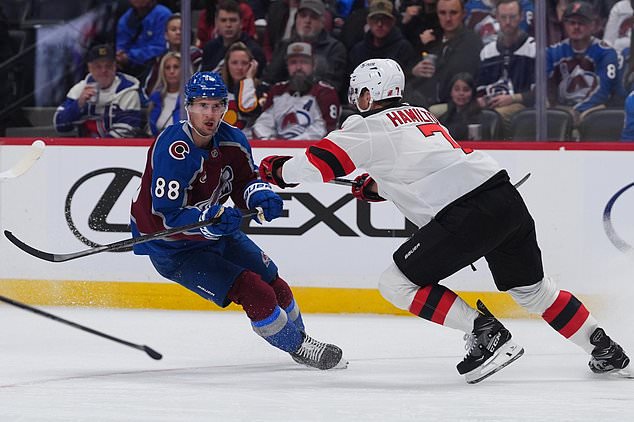 New Jersey Devils defenseman Dougie Hamilton, right, checks Colorado Avalanche center Martin Necas as he pursues the puck in the first period of an NHL hockey game Wednesday, Oct. 28, 2026, in Denver. (AP Photo/David Zalubowski)