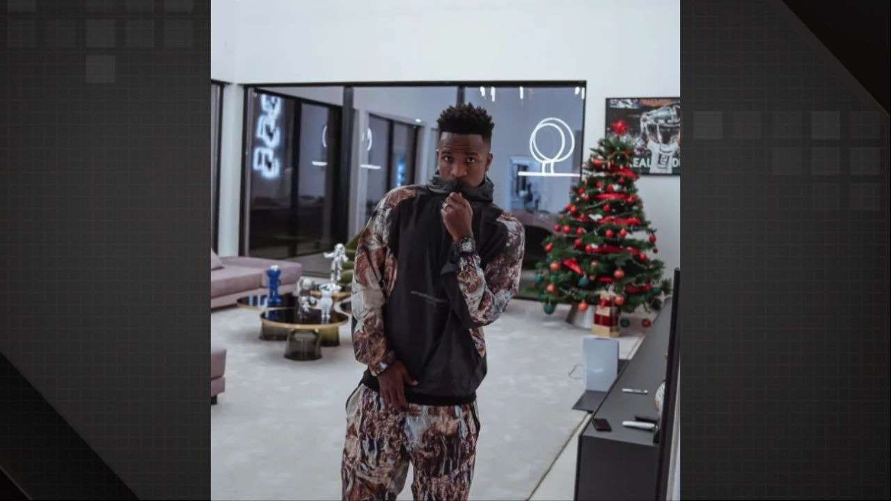 Vini Jr. em moletom estampado, posa na sala com árvore de Natal, relógio e decoração moderna
