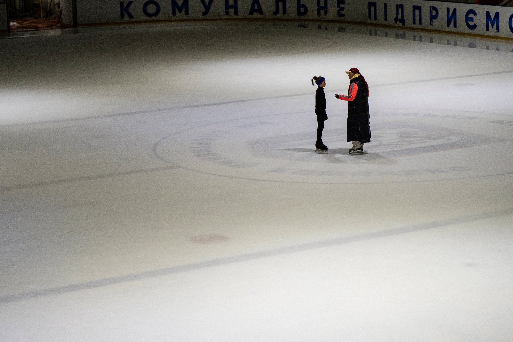 Une entraîneuse ukrainienne échange avec une jeune patineuse sur une patinoire à Kiev, le 16 octobre 2026