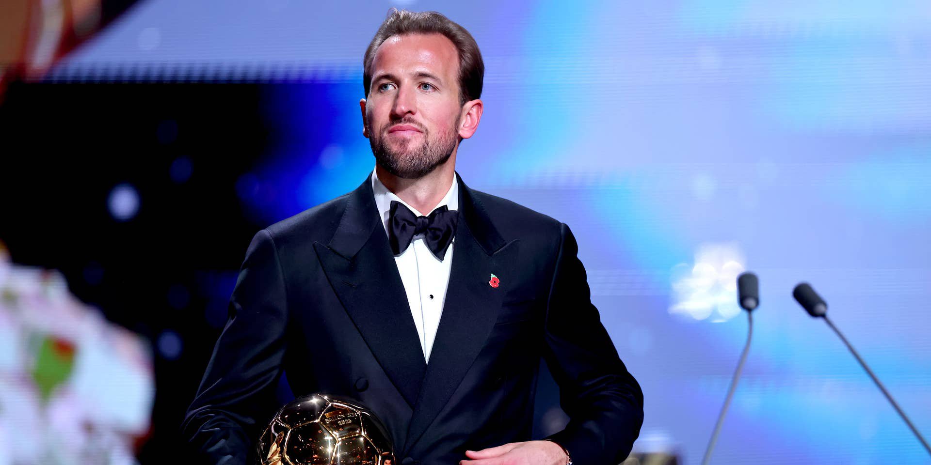 Ein Mann im Smoking hält den Ballon d'Or-Pokal bei einer Preisverleihung auf der Bühne.