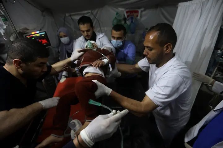 Palestinian medics carry a young wounded in the Israeli bombardment of the Gaza Strip, to the Kuwaiti Hospital in Rafah