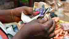 A market vendor with painted nails counts naira in south-eastern Nigeria - 2023