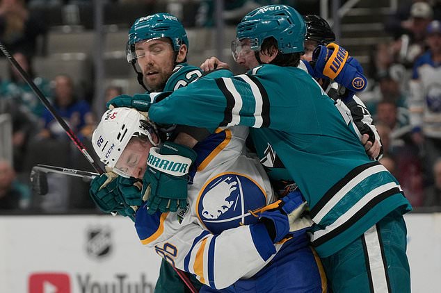 Buffalo Sabres center Noah Östlund, bottom, is grabbed by San Jose Sharks center Barclay Goodrow, top left,, and defenseman Michael Kesselring during the second period of an NHL hockey game, Tuesday, Oct. 27, 2026, in San Jose, Calif. (AP Photo/Jeff Chiu)
